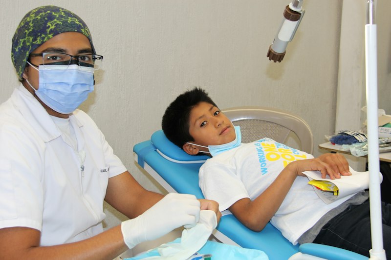 Criança sendo atendida por dentista na cadeira odontológica